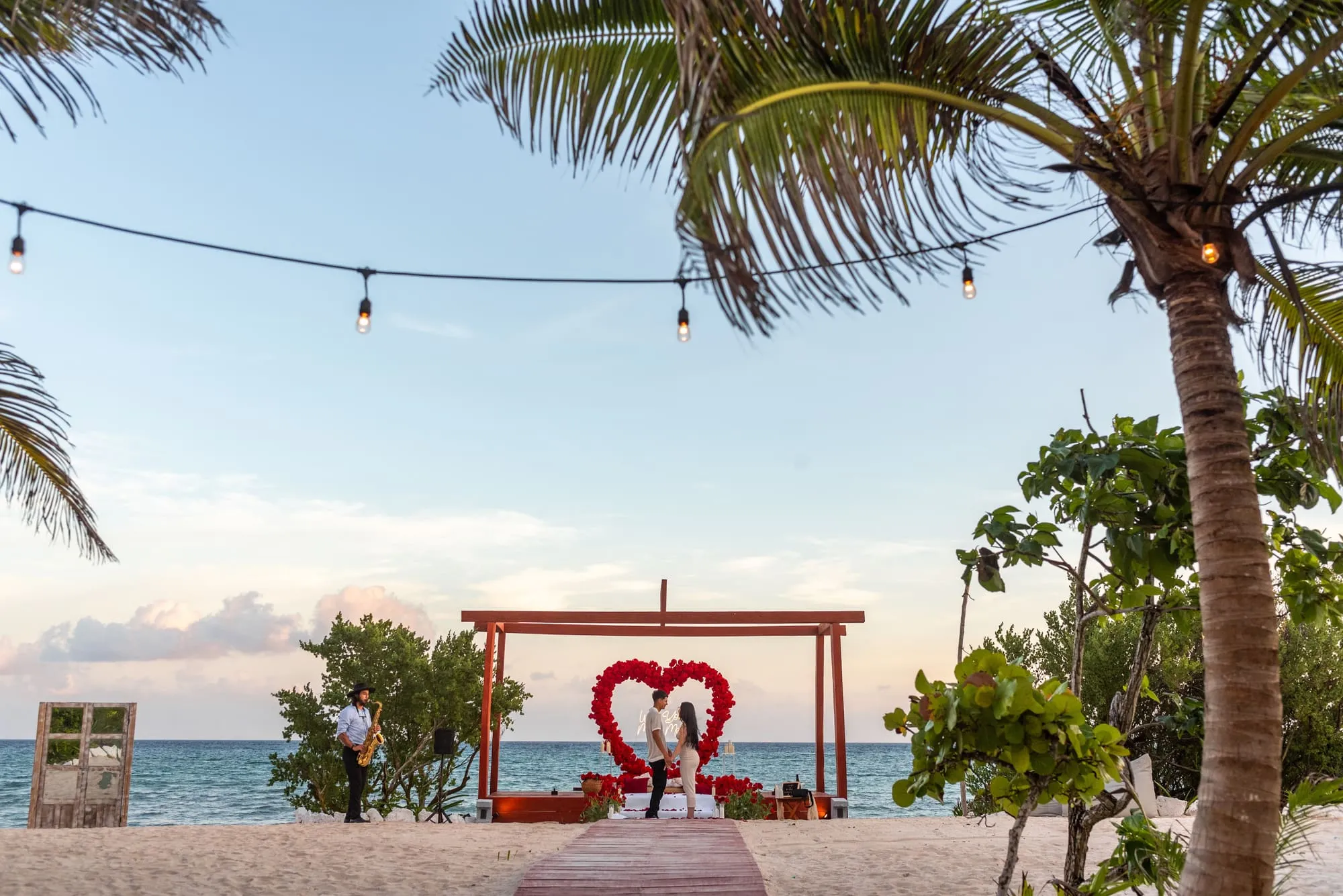 A beach proposal framed by palms, with the Caribbean sea beyond