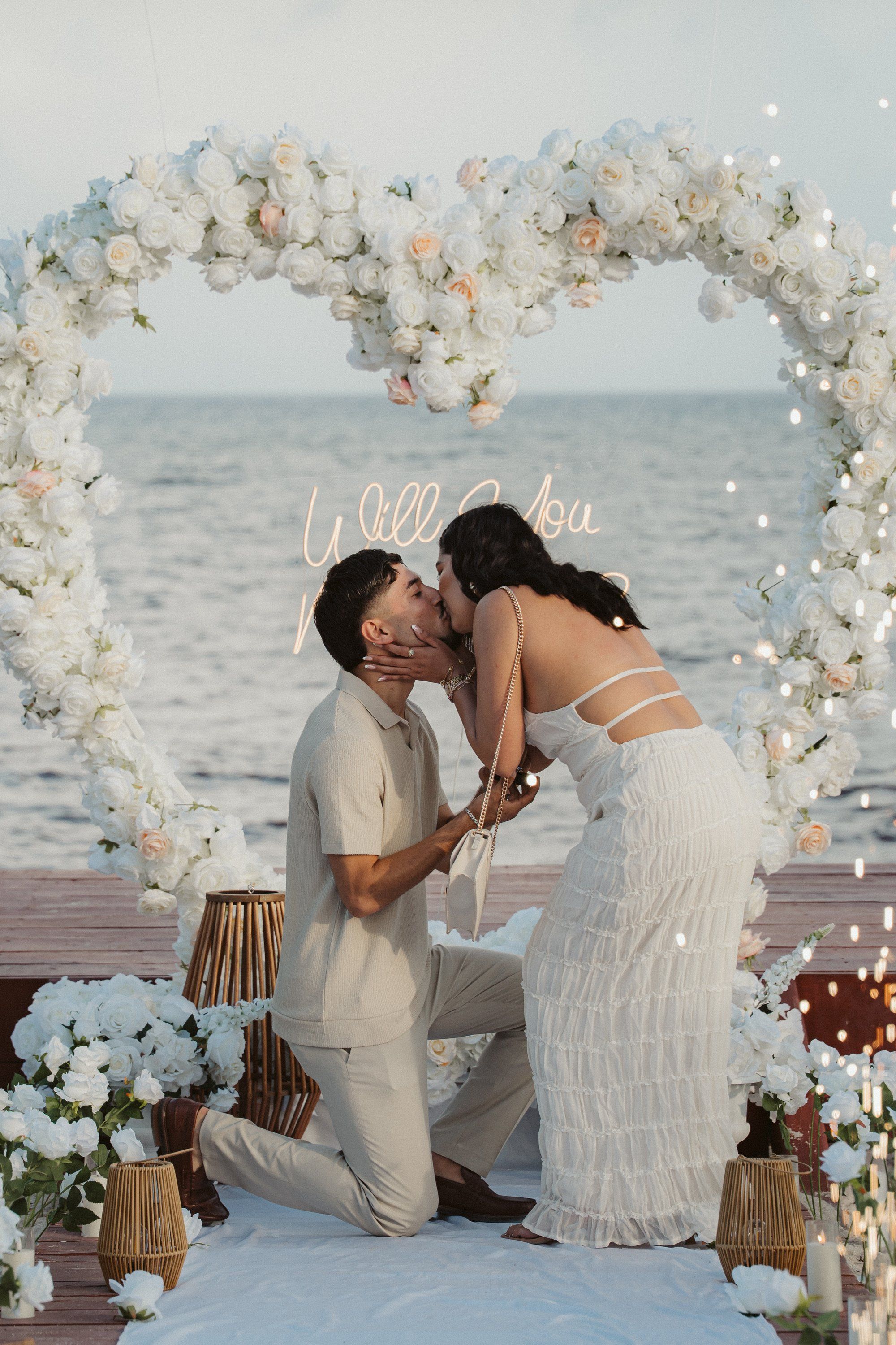 Romantic oceanfront marriage proposal moment on a private balcony in Cancun as the sun sets over the turquoise horizon.