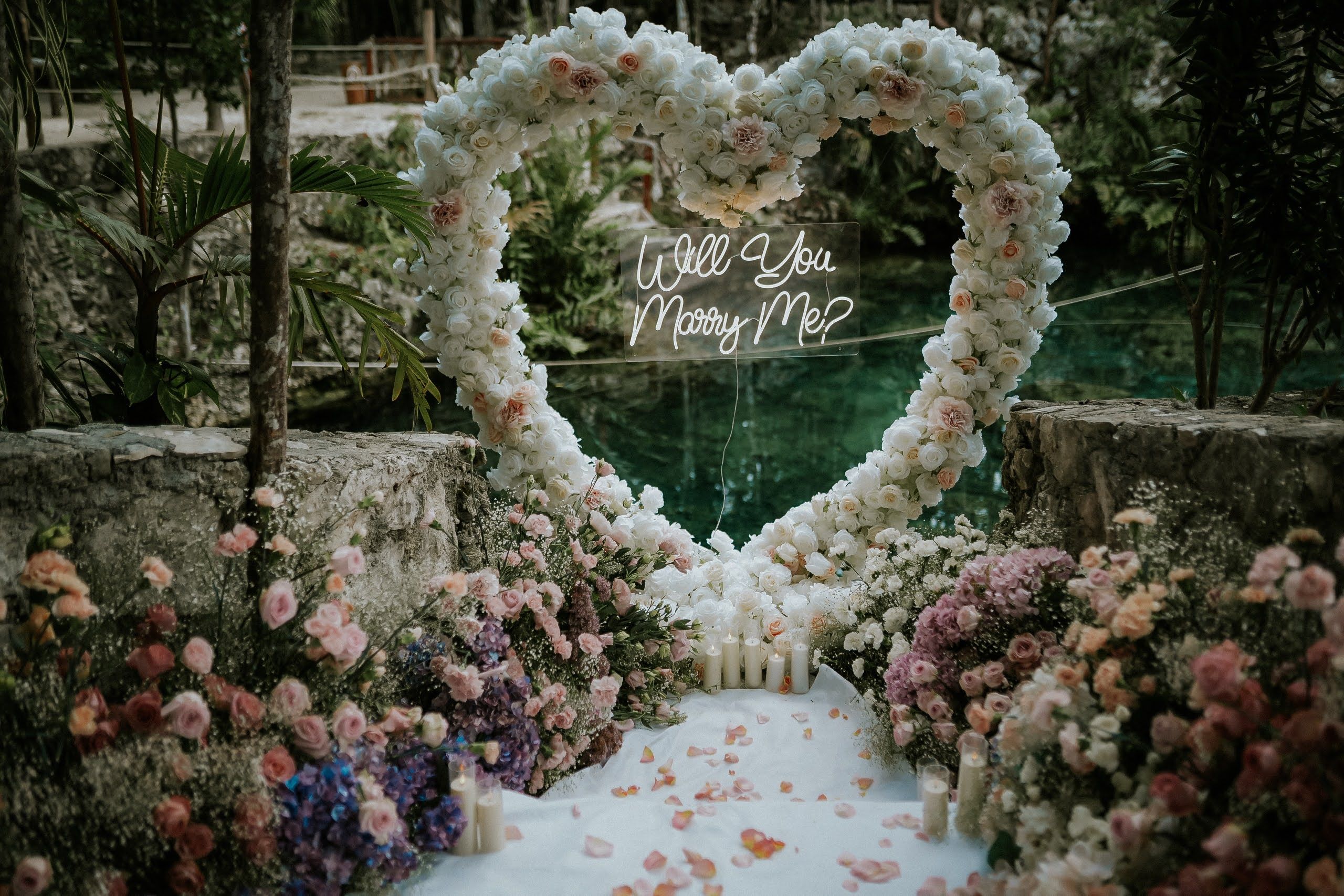 Happy couple embracing in a mystical Mayan cenote in Akumal after a successful surprise proposal setup with candles and rose petals.