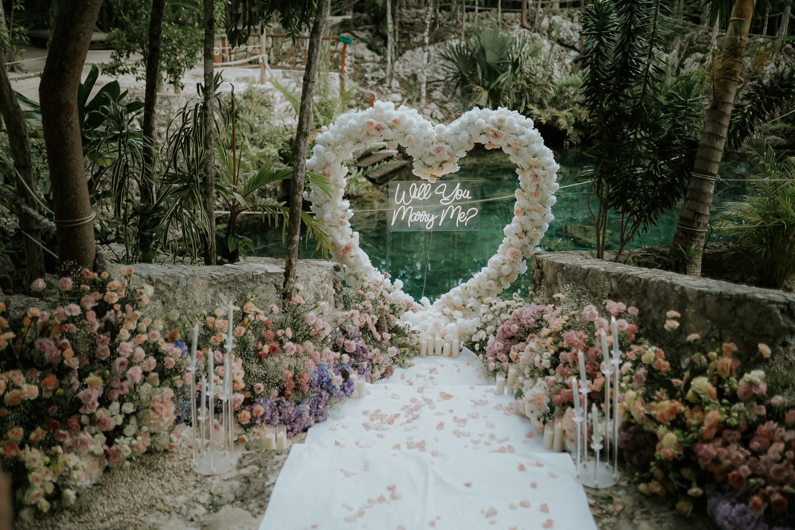 Romantic marriage proposal in an ethereal limestone cavern cenote near Playa del Carmen with soft sunlight filtering through the jungle canopy above.