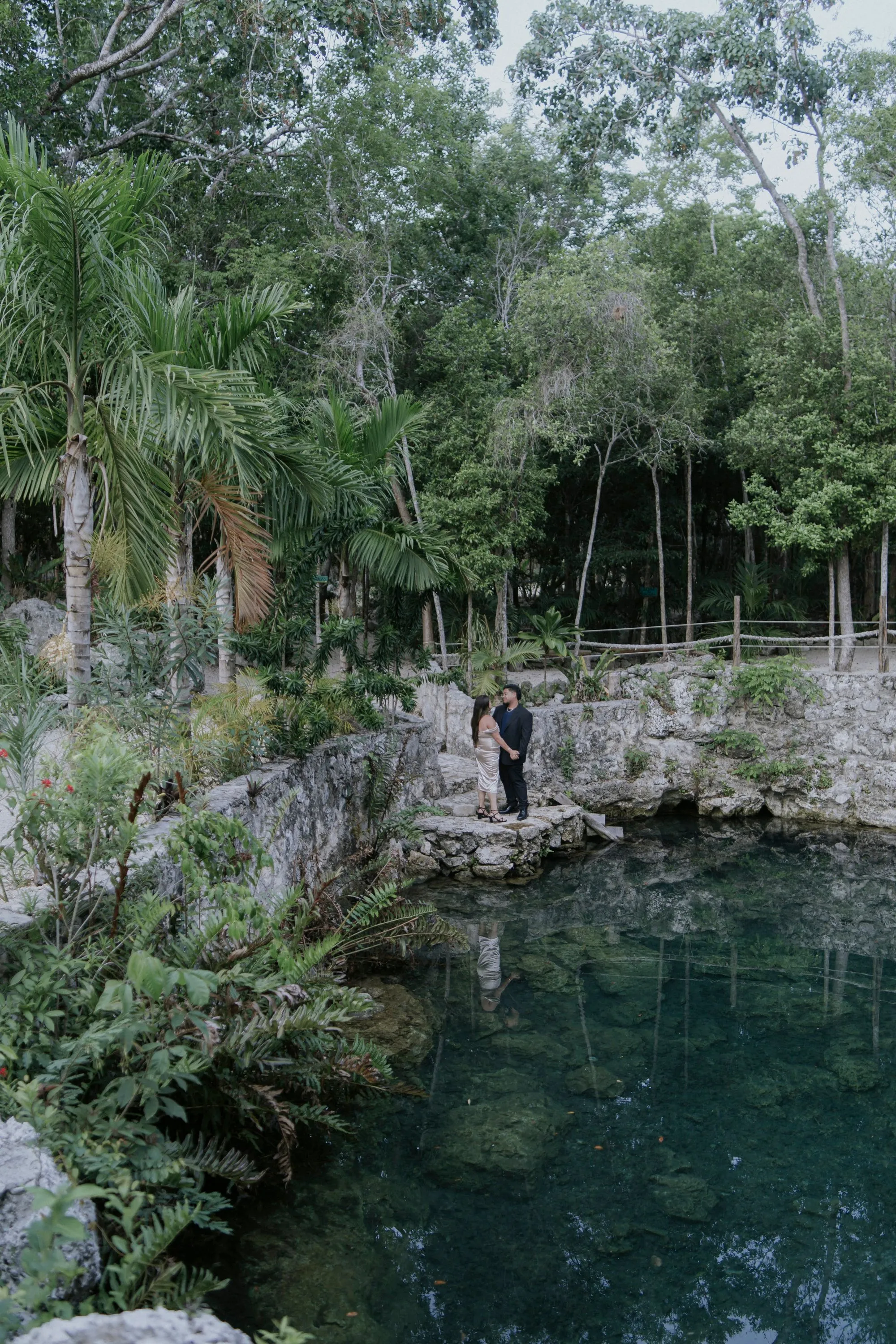 A couple standing beside a natural cenote surrounded by jungle in Riviera Maya