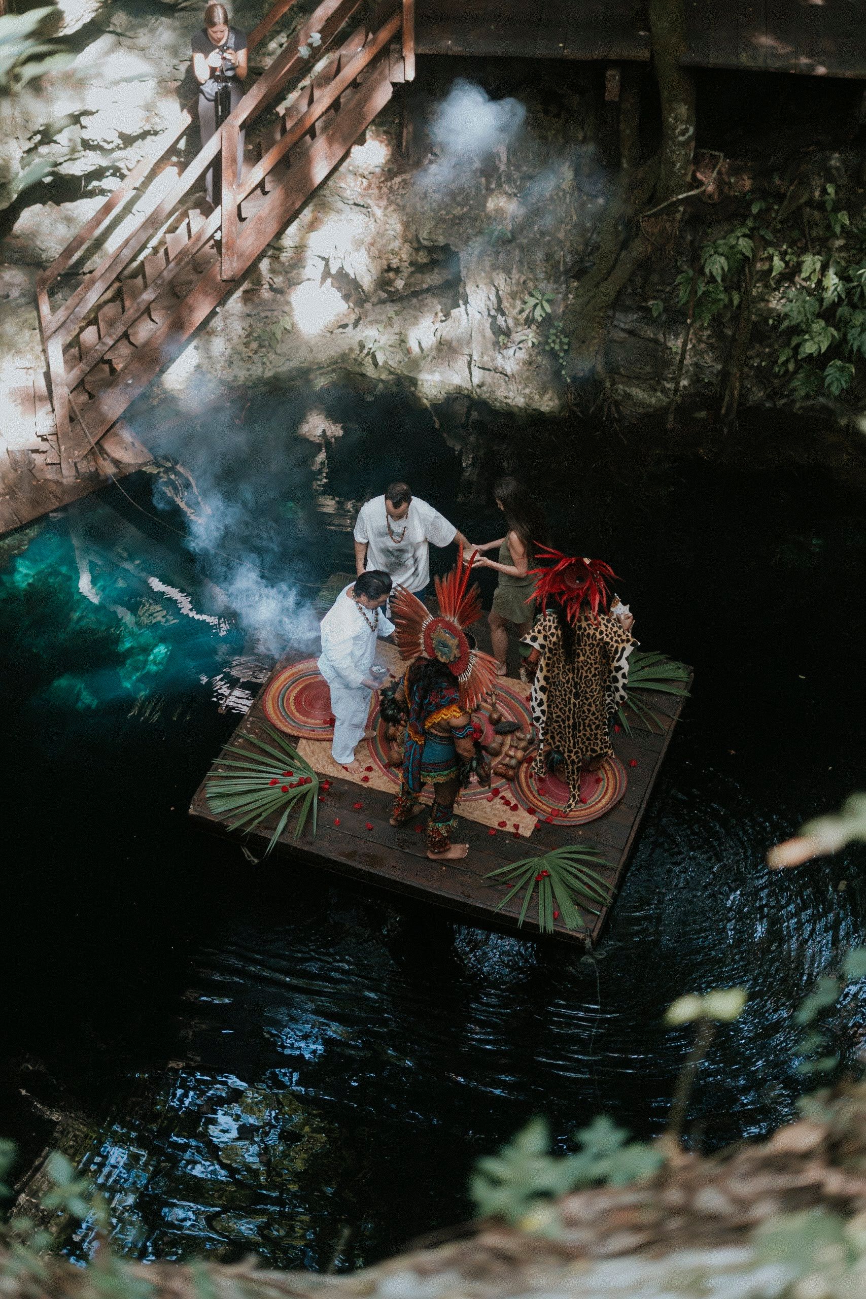 Marriage proposal setup at a jungle cenote sanctuary in Akumal featuring a wooden dock, white linens, and lush tropical greenery.