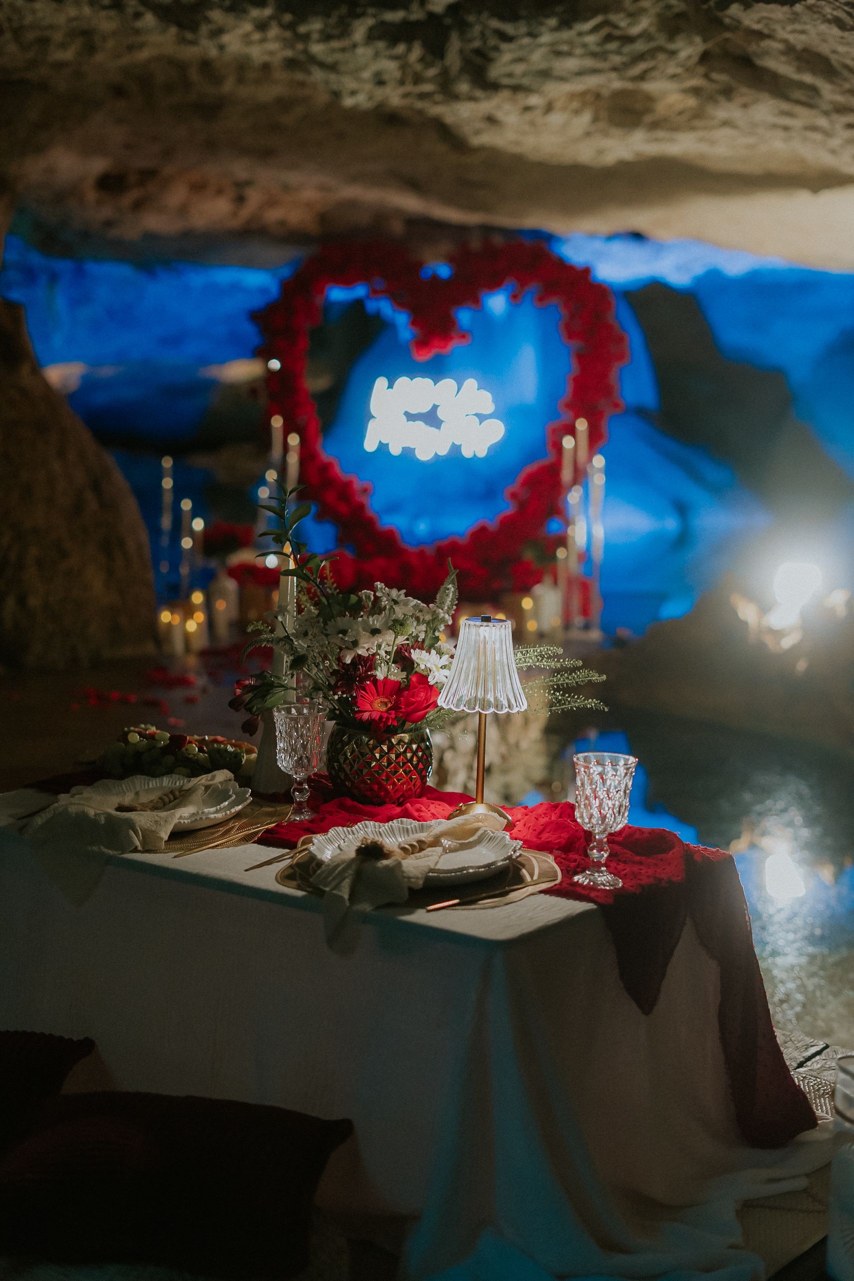 Spectacular marriage proposal inside a deep cenote grotto near Cancun with detailed floral decorations and a romantic blue-lit atmosphere.