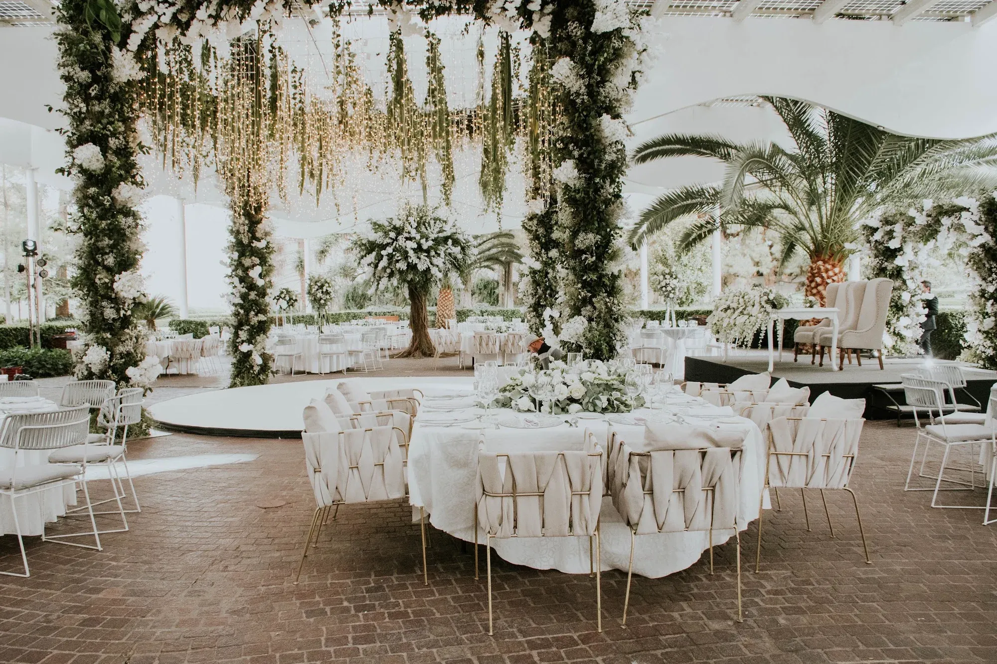 Full-service wedding setting with white florals and tropical greenery