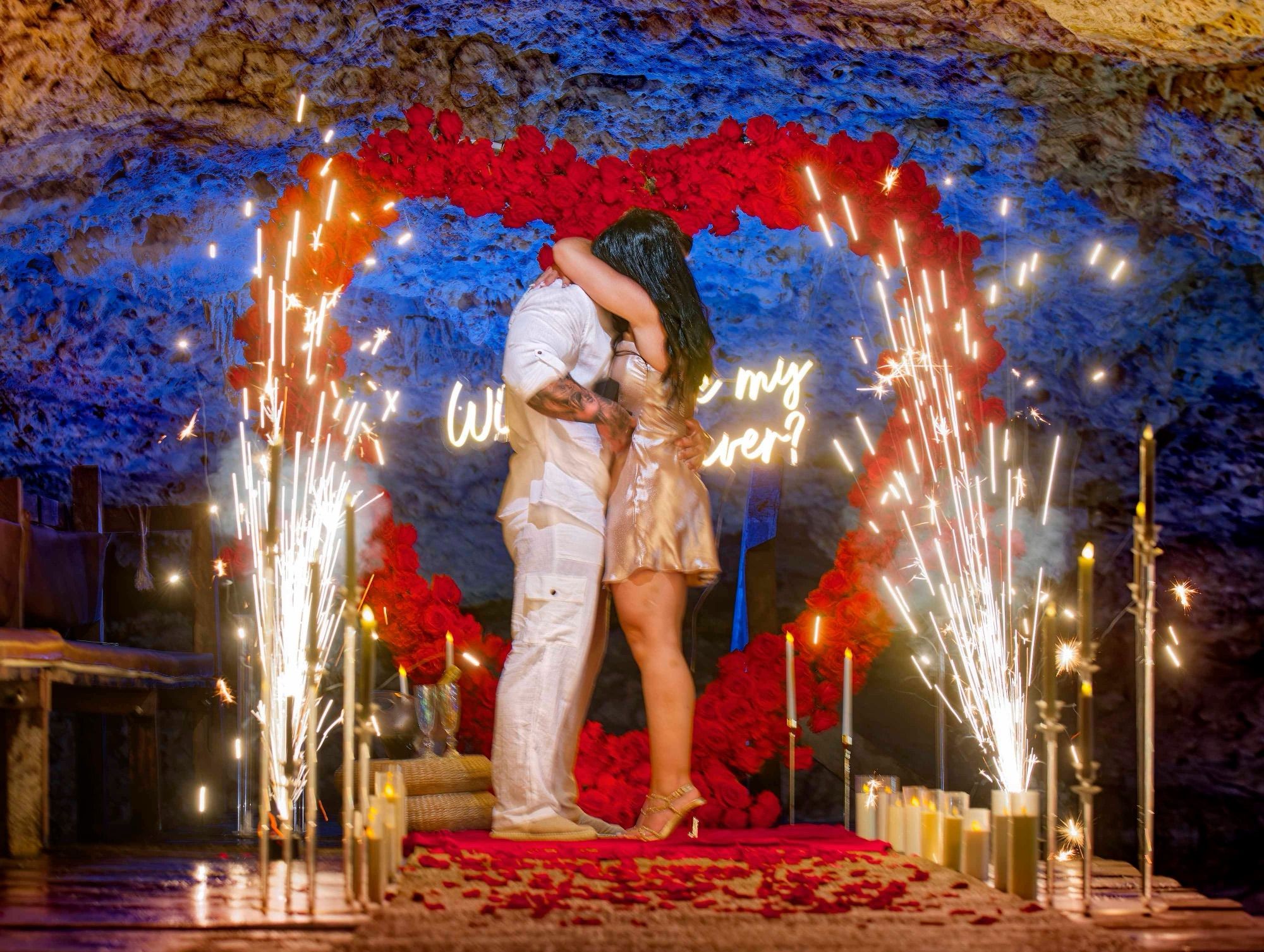Intimate cenote proposal with the couple embracing inside a rose heart arch framed by cold sparklers