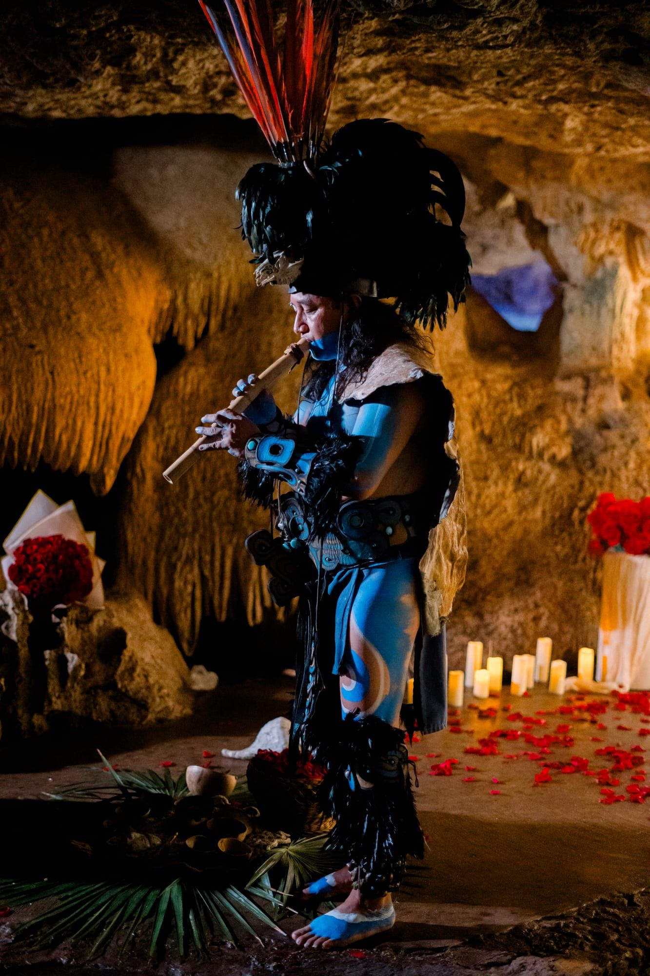 Mayan blessing musician performing in a candlelit Riviera Maya cenote cave beside a red rose proposal setup.