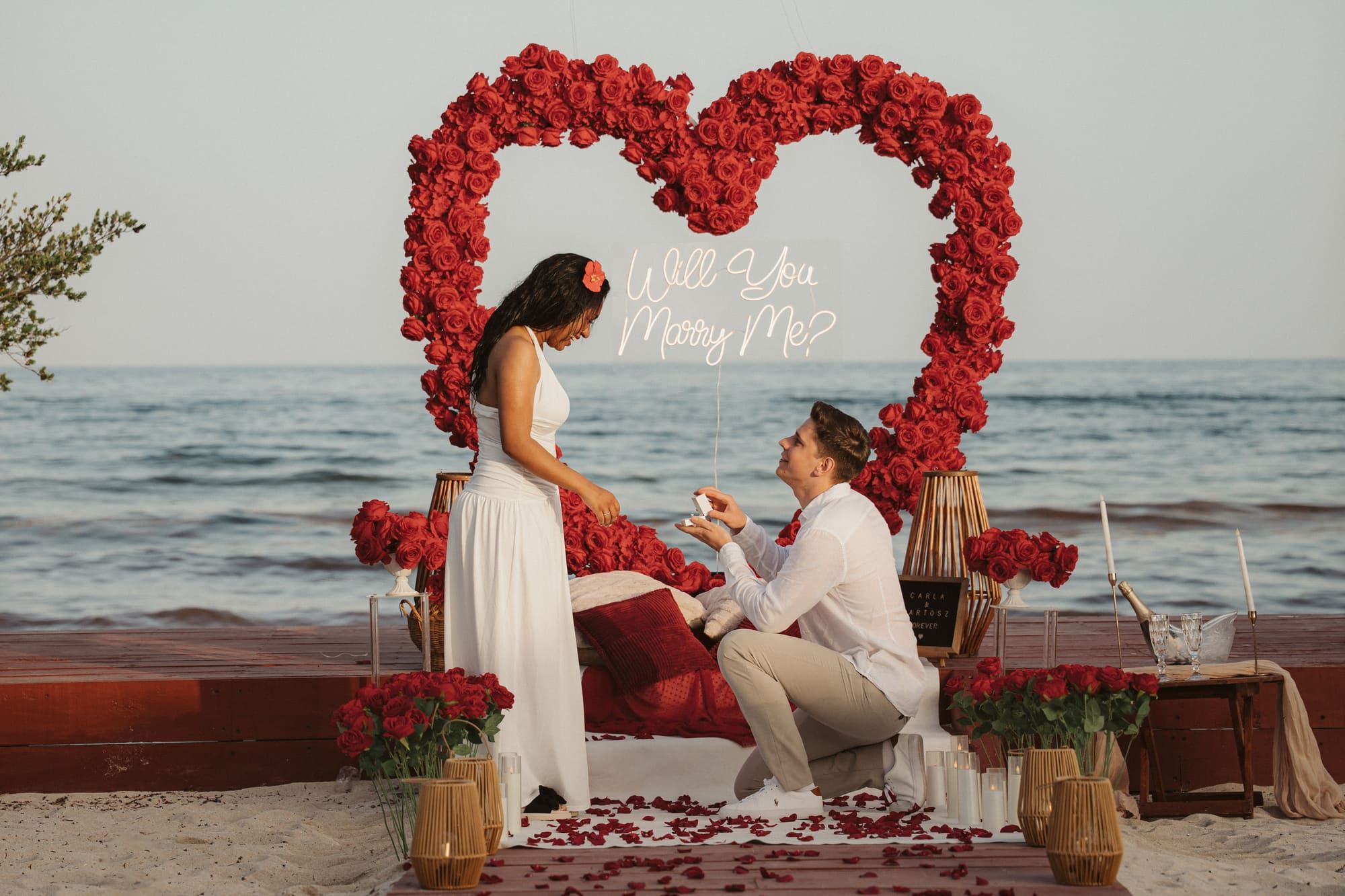 Romantic moment of a man kneeling in the sand to propose to his partner on a beautiful Caribbean beach.