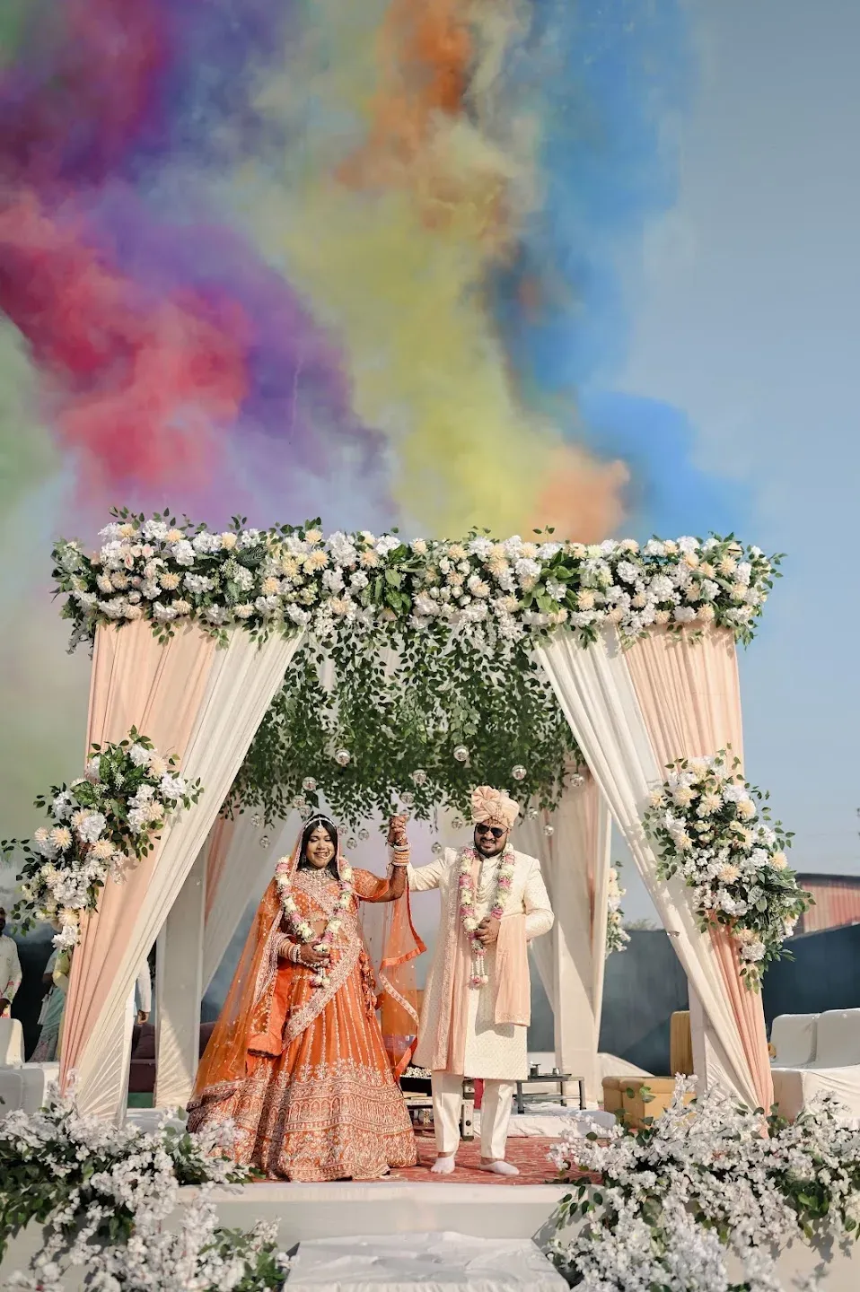 Wedding party beneath colorful smoke at an outdoor ceremony